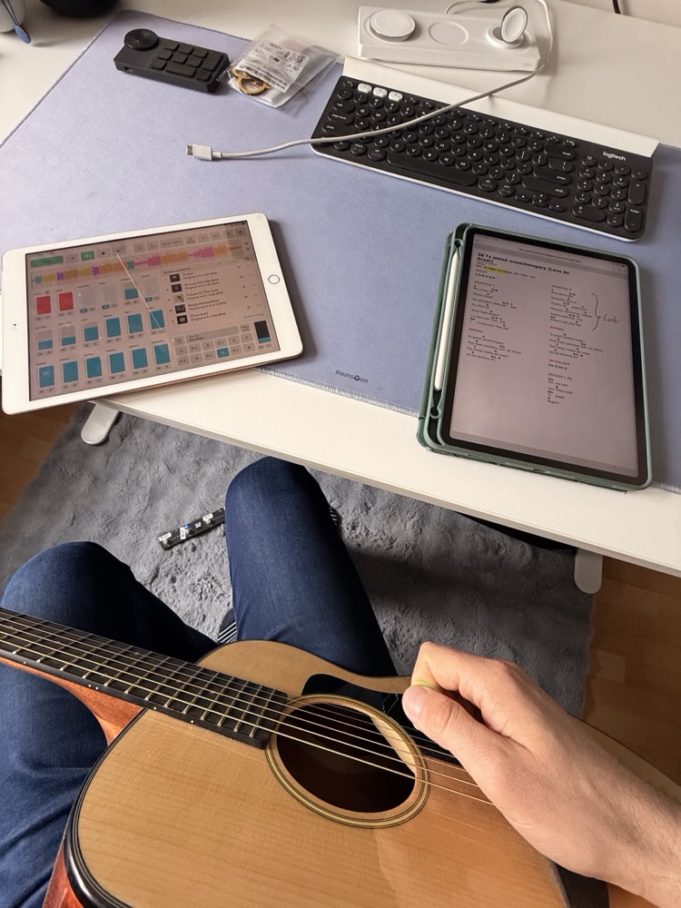 Gitara na kolanach, na biurku tablety z sesją nagraniową i akordami